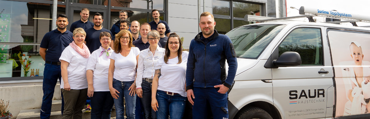 Das gesamte Team von Saur Haustechnik vor dem Firmengebäude mit den Servicefahrzeugen in Tübingen-Lustnau
